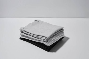 Gri arkaplanda gri, siyah ve beyaz renkli katlanmış tişörtlerin yakın çekim görüntüleri