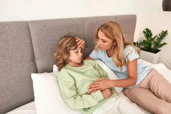 A picture of a mother checking her sons fever — Stock Photo, Image