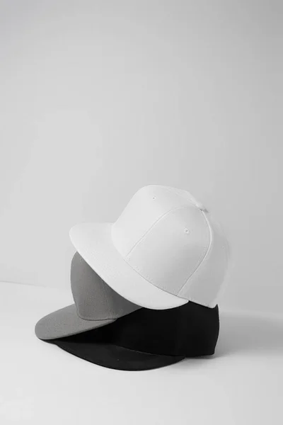 Set of three blank monochrome white, gray and black baseball cap isolated over light background — Stock Photo, Image