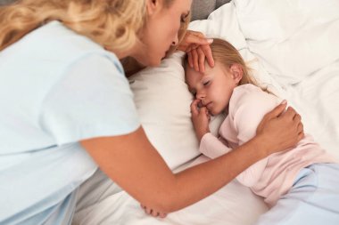 Anne kızının ateşini ölçüyor.