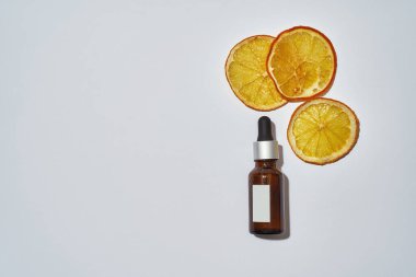 Portakalın yanında içi yağ dolu boru şişesi.