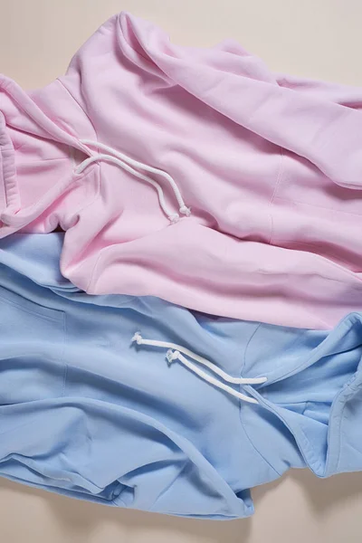 Pose plate de deux sweat à capuche en coton blanc pastel bleu et rose isolé sur fond beige pâle — Photo