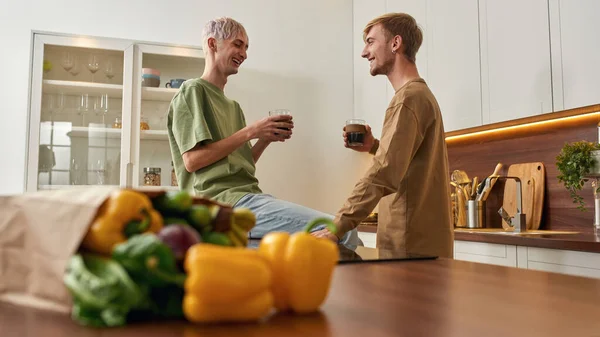 Щаслива пара чоловіків розмовляє біля столу на кухні — стокове фото