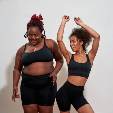 Kameranın önünde seksi hareketler yapan iki kadının fotoğrafı.