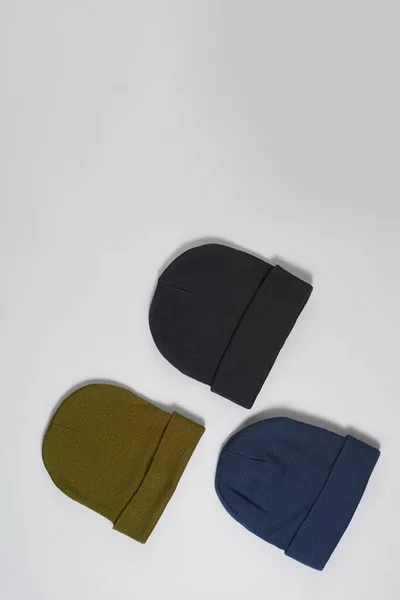 카키색, 짙은 청색, 검은 색 히프 스터 비니 모자 세트가 회색 배경 위로 따로 놓여 있다. — 스톡 사진