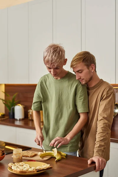 Pareja homosexual de pie cerca de la mesa en la cocina moderna —  Fotos de Stock