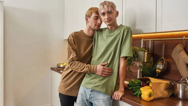 Amantes masculinos abrazándose mientras están de pie en la cocina moderna — Foto de Stock