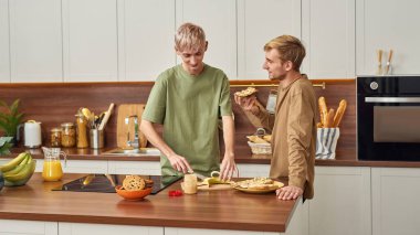 Mutlu aynı cinsiyetten erkekler konuşuyor ve atıştırmalıkları hazırlıyor.