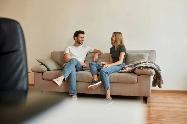 Młoda para siedzi na kanapie i prowadzi rozmowę — Zdjęcie stockowe