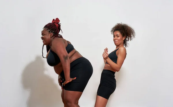 Zwei Afro-Frauen mit S und XXL-Größe stehen über der Wand — Stockfoto