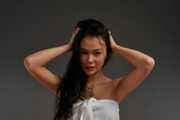 Joven hermosa asiático medio desnudo mujer en baño toalla tousled su cabello con un mano —  Fotos de Stock