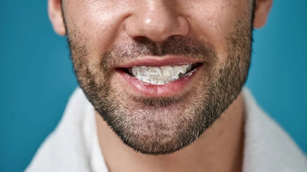 Close-up van de man met de baard glimlachen op de camera met tandpasta in zijn mond na het poetsen tanden geïsoleerd over blauwe achtergrond — Stockfoto