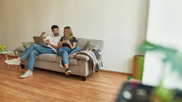 Giovane uomo con computer portatile in ginocchio discute dettaglio di lavoro con la sua ragazza — Foto Stock