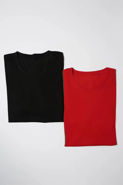 Duas camisas de algodão preto e vermelho coloridas dobradas isoladas no fundo branco. Modelo de tees leigos planos — Fotografia de Stock