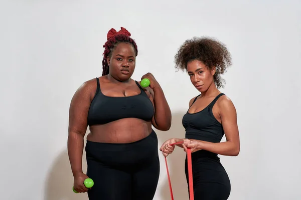 Imagen de dos mujeres afro sosteniendo pesas y saltando la cuerda, todos y cada uno de los cuerpos en este mundo es hermoso — Foto de Stock