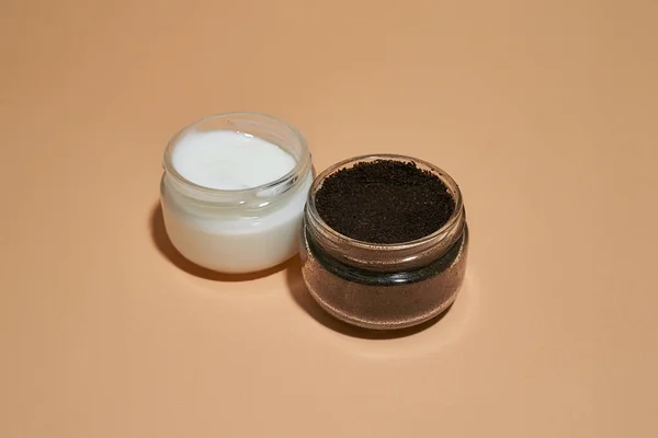 Coffee scrub and cosmetological cream in open round cans