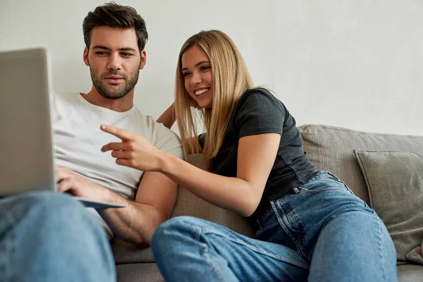 Una pareja en el sofá discutiendo algo interesante en el monitor del portátil —  Fotos de Stock