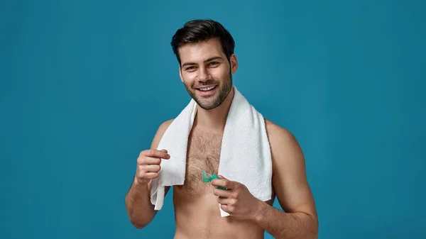 Studio shot of smiling naked man with towel around his neck holding dental floss for flossing his teeth, posing isolated over blue background — Stock Photo, Image