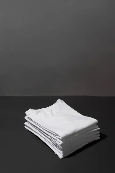 하얀 면 셔츠가 접혀 있는 천 조각 이어두운 회색 배경 위로 분리되어 있다 — 스톡 사진