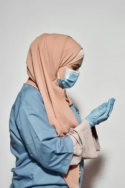 Yüz maskeli genç Arap kadın doktor yan poz veriyor. — Stok fotoğraf