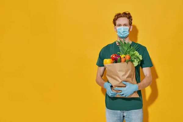 Joven mensajero caucásico sosteniendo paquete con verduras —  Fotos de Stock