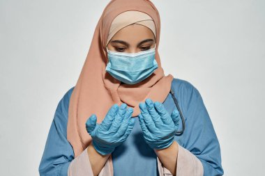 Genç Arap doktor eldivenli ellere bakıyor.