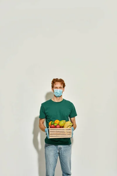 Mladý kavkazský kurýr drží krabici šťavnatého ovoce — Stock fotografie