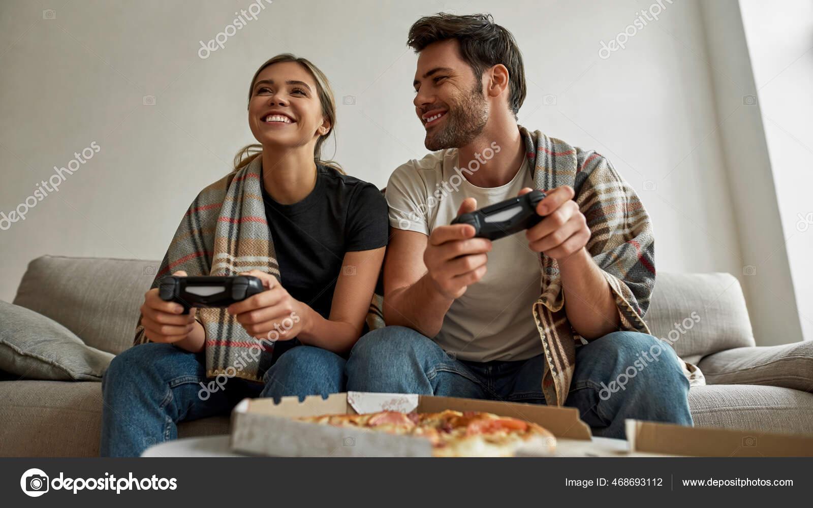 Happy Couple Sitting On The Sofa Playing Video Games Using