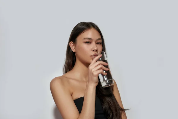 Νεαρή Ασιάτισσα πίνει νερό από γυαλί — Φωτογραφία Αρχείου
