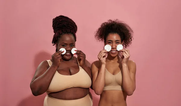 Un par de amigas afro se manchan la cara con esponjas de algodón — Foto de Stock