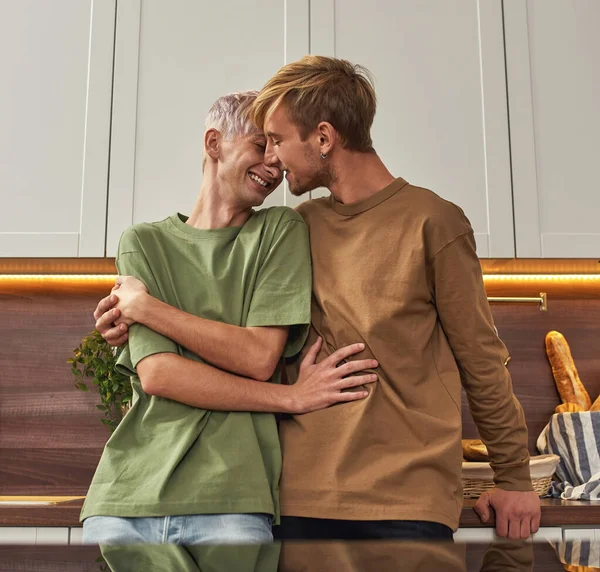 Feliz pareja de hombres homosexuales abrazándose en la cocina moderna — Foto de Stock