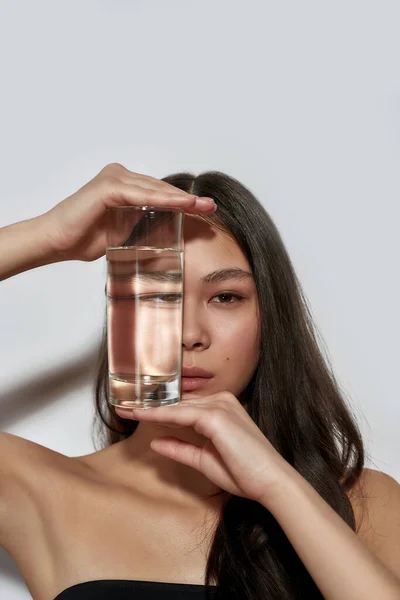 Νεαρή Ασιάτισσα που κρύβεται πίσω από γυαλί με νερό — Φωτογραφία Αρχείου