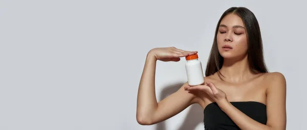 Junge Asiatin hält Vitaminpäckchen in den Händen — Stockfoto