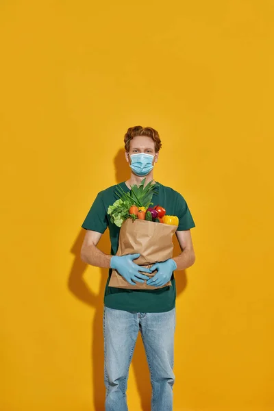 Courier holding packet with fresh vegetables — Stock Photo, Image