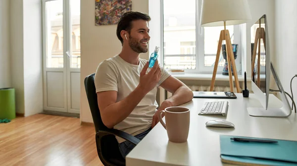 Young man demonstrates his antiseptic to his colleague on video — Stock Photo, Image