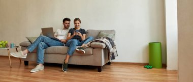 Genç ve güzel bir çift ellerinde aletlerle kanepede oturuyor. 