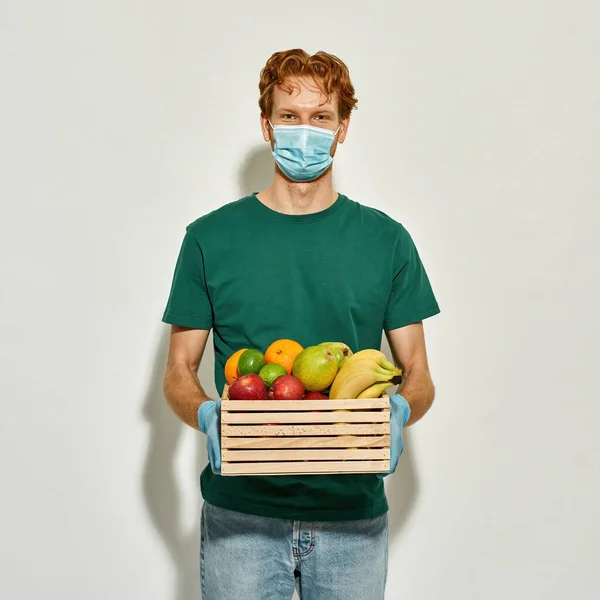 Joven mensajero caucásico sosteniendo caja de fruta fresca —  Fotos de Stock