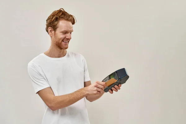 Giovane rosso sorridente uomo compra con strisciare la sua carta — Foto Stock