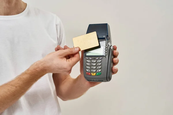Cut picture of a young man applies credit card to the payment terminal