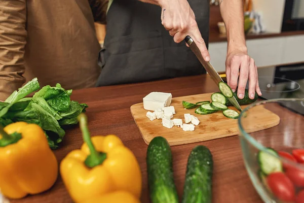 Aynı cinsiyetten erkek çift salata için salatalık kesiyor. — Stok fotoğraf