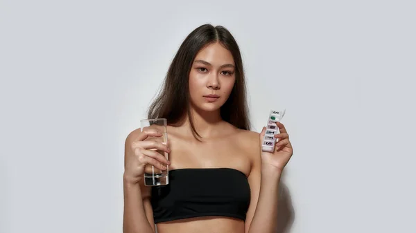 Mooi jong aziatisch meisje holding wekelijks pil organisator — Stockfoto