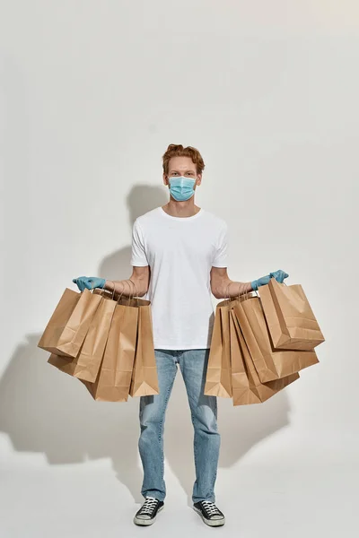 Repartidor que tiene un montón de bolsas de papel colgadas en sus manos —  Fotos de Stock
