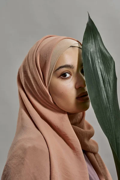 Giovane ragazza araba in hijab accanto alla foglia verde — Foto Stock