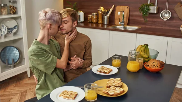 Homosexual male couple ready to kiss at kitchen table — Stock Photo, Image