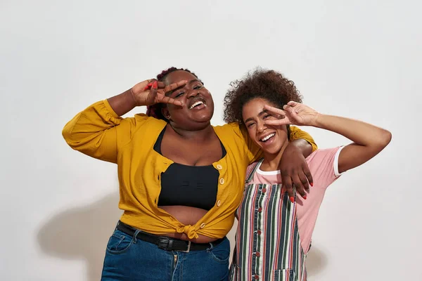 Due afro-donne in piedi davanti al muro e mostrando la pace — Foto Stock