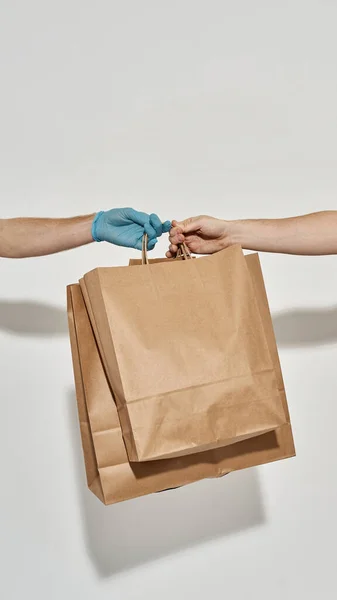 Hand in a rubber glove giver paper bag in other hand