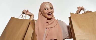 Elinde paketler olan mutlu genç Arap kızın portresi.