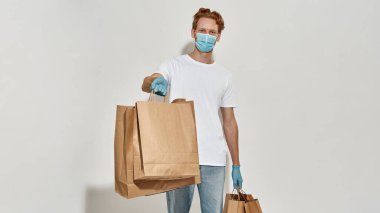 Teslimatçı bir sürü kağıt torba tutuyor ve onları kamerada gösteriyor.