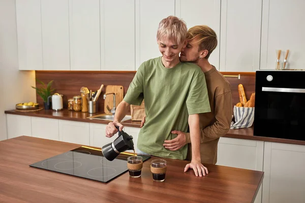 在现代厨房里喝早茶的时候，温存的同性恋男女拥抱在一起 — 图库照片