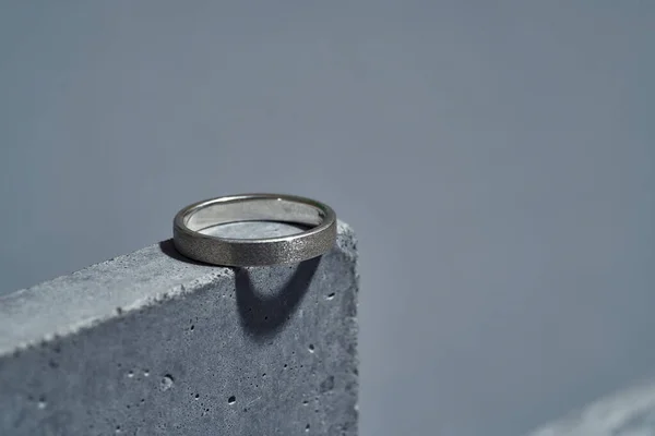 Μακρό πλάνο από ασημένιο δαχτυλίδι στο στοιχείο σκυροδέματος που απομονώνεται σε γκρι φόντο — Φωτογραφία Αρχείου